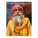 An Indian holy man with a long grey beard poses for a photo. Varanasi, India.